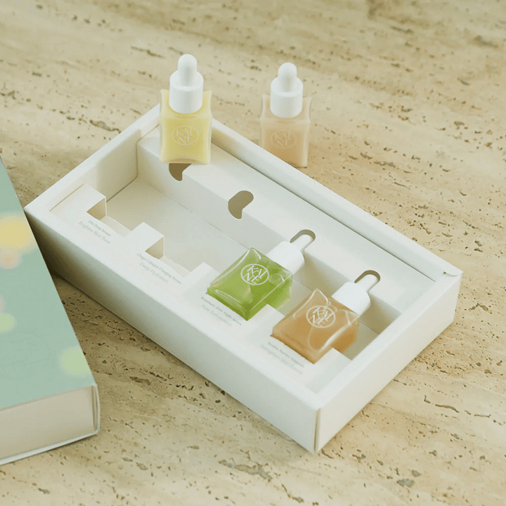 Fyra färgglada serumflaskor från KAINE Serum Discovery Kit med pipettkork, designade för att möta olika hudbehov i en minimalistisk och stilren förpackning.