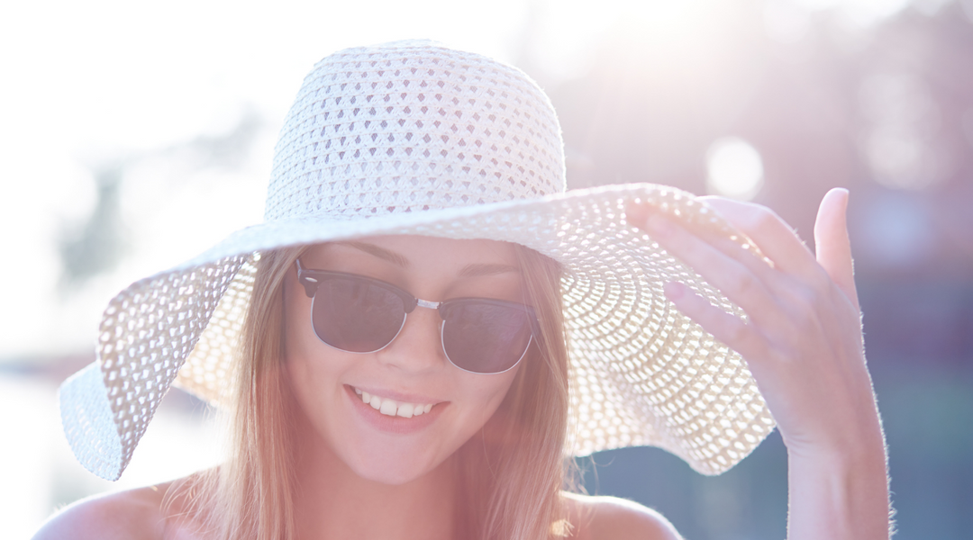 En kvinna som bär solglasögon och en hatt.