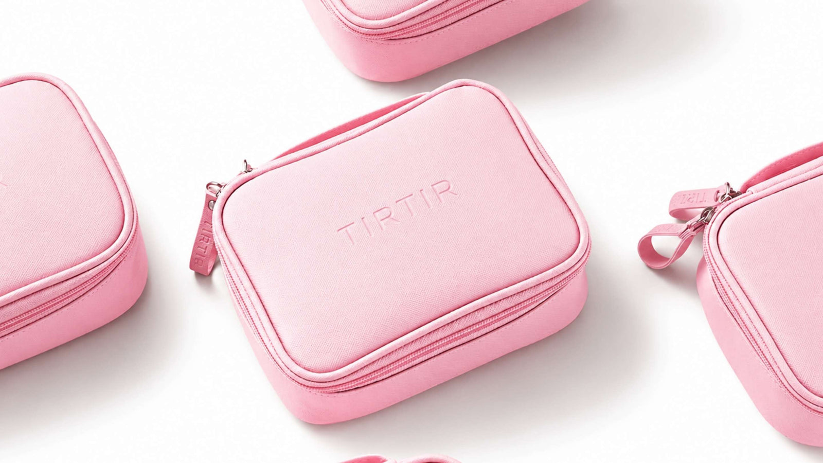 Bilden visar eleganta rosa necessärer från märket TIRTIR. Dessa väskor är designade med märkets namn präglat i samma ton som väskan, vilket ger en subtil och sofistikerad look.