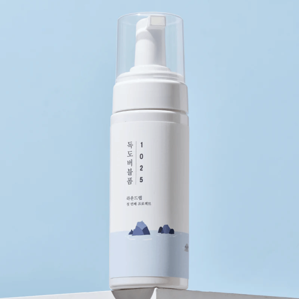  The product is a "1025 Dokdo Bubble Foam" from ROUND LAB, packaged in a white pump bottle with a minimalist design. It is intended for deep cleansing of the face without irritation.