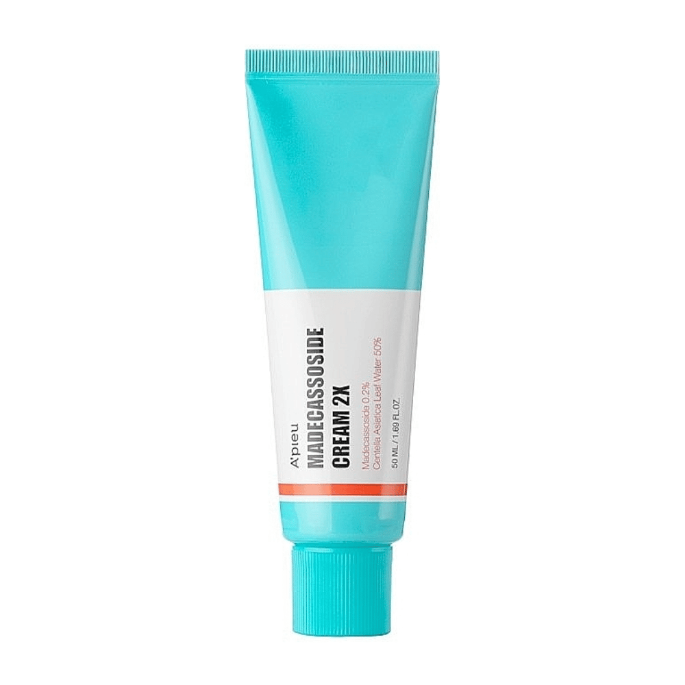 A tube with A'PIEU Madecassoside Cream 2X, with a light turquoise color at the top that transitions to white towards the bottom. The tube has clear text indicating the brand and product name as well as the active ingredient Madecassoside 2%. An orange accent color runs as a stripe around the tube. The product appears to be a skin cream focused on skincare and repair. The background is neutral to keep the focus on the product.