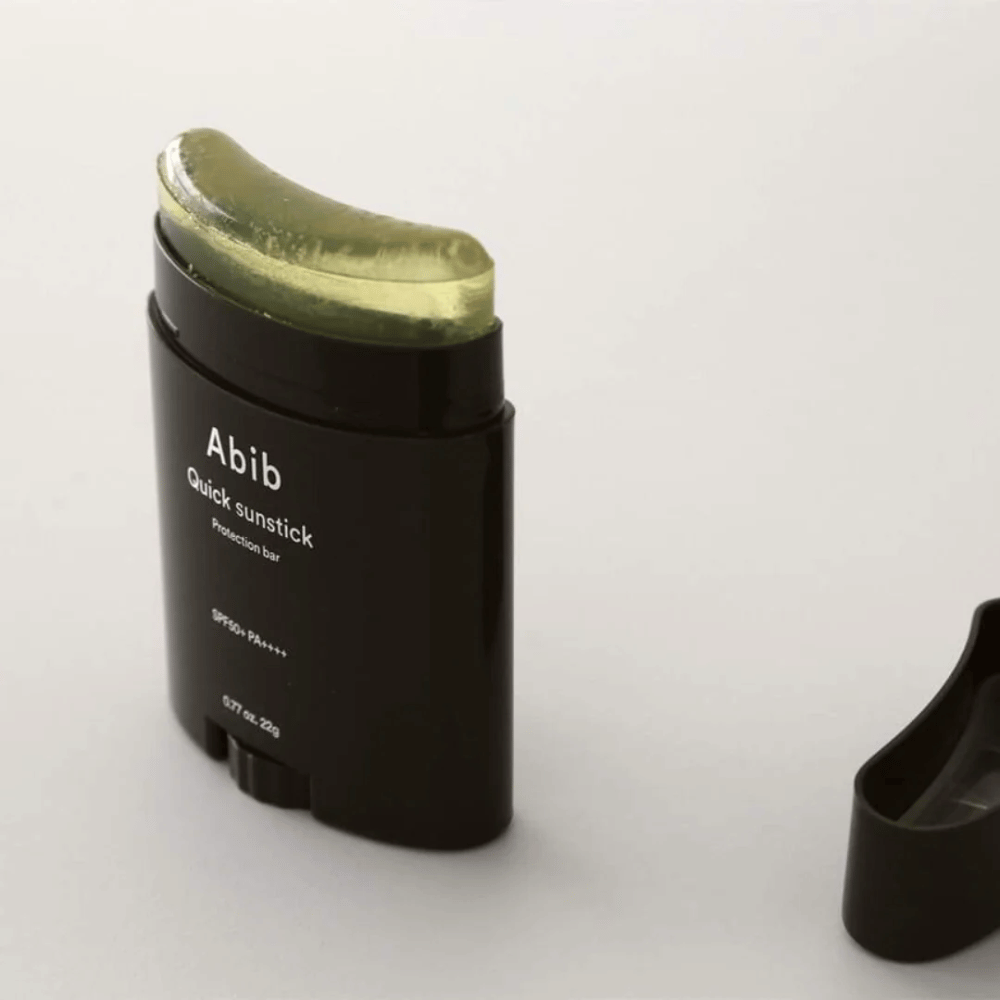 A black tube with a green cap, containing Quick Sunstick Protection Bar SPF50+ PA++++ 22g from Abib for sun protection.