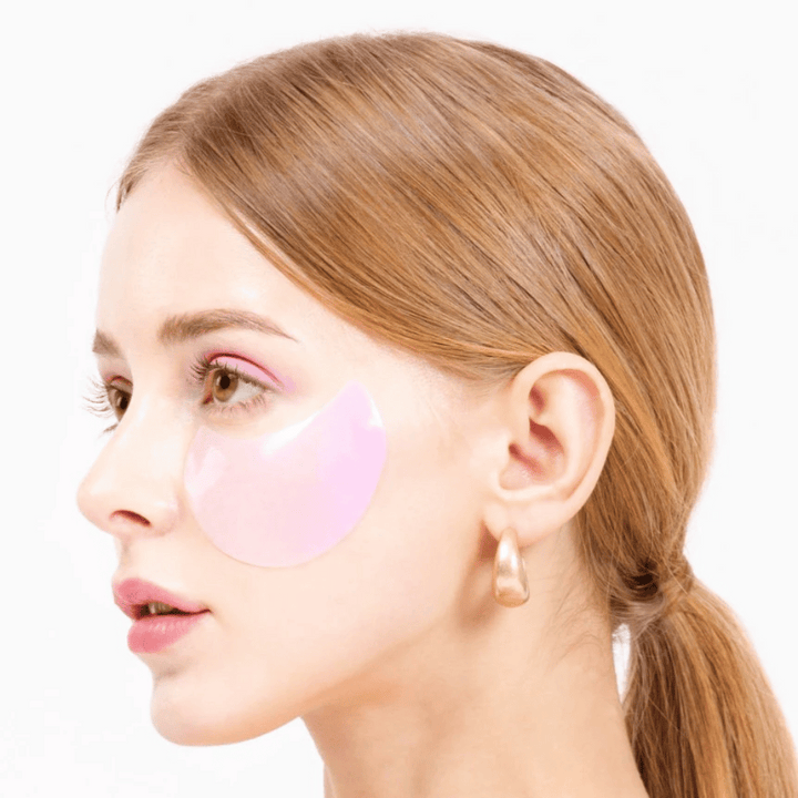 Modell bär ett rosa hydrogel eye patch under ögat, återfuktande och hudföryngrande.