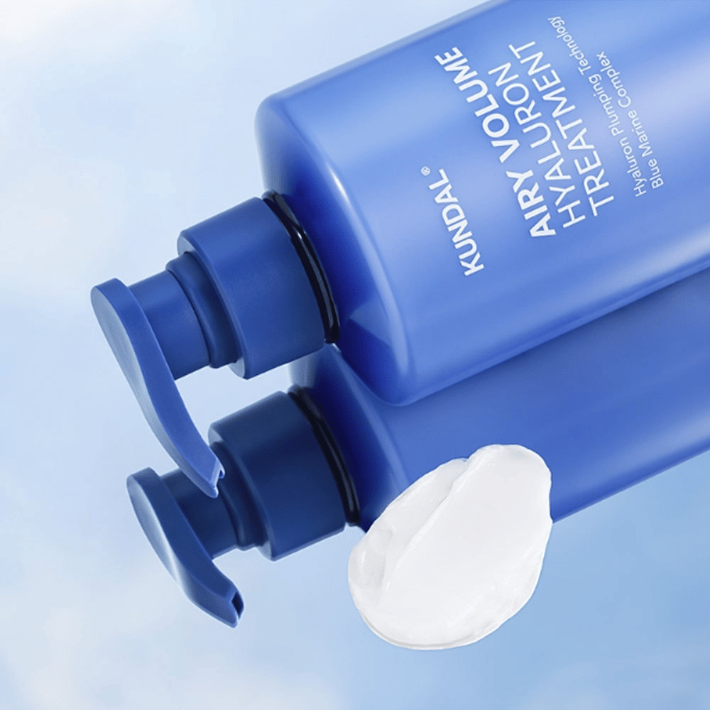 KUNDAL Airy Volume Hyaluron Treatment in blue pump bottle lying down, with white cream product visible next to it.
