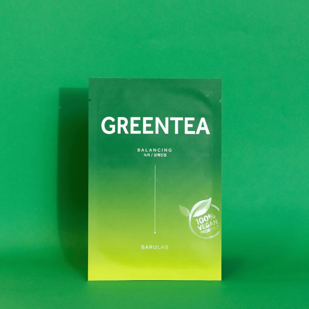A package from BARULAB for a "GREENTEA Balancing" mask, marked as "100% Vegan Product". The packaging's color transitions from dark green at the top to lighter green at the bottom, against a uniform green background.