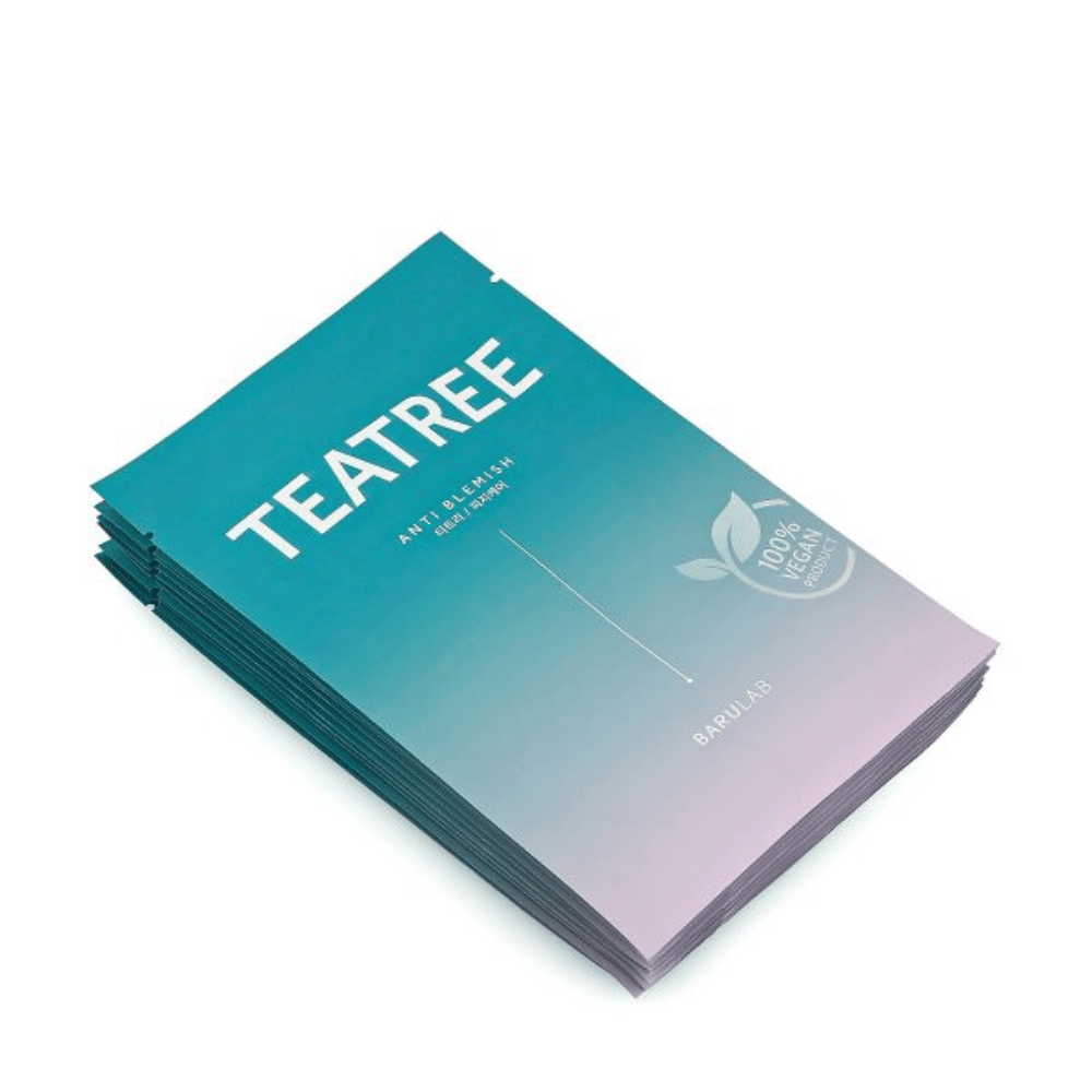 A pile of packages of BARULAB "TEATREE Anti Blemish" masks, all labeled as "100% Vegan Product". The packages have a uniform turquoise color.