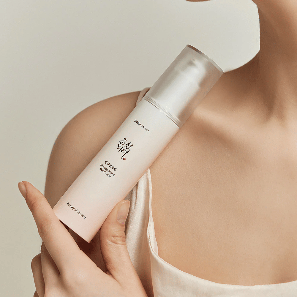 A woman holding a bottle of Beauty of Joseon's Ginseng Moist Sun Serum SPF 50+ PA++++, which provides SPF 50+ PA++++ protection and skincare benefits.