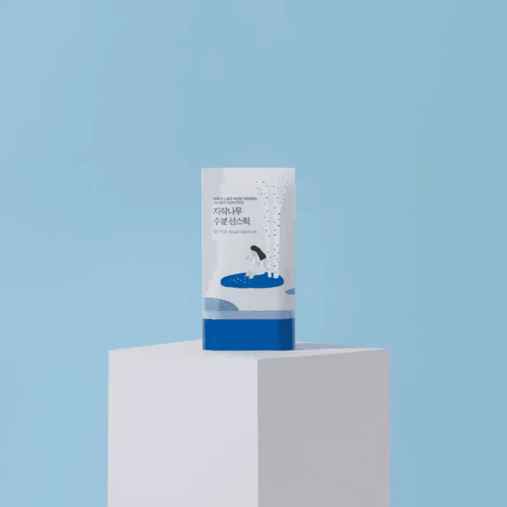 ROUND LAB Birch Juice Moisturizing Sun Stick SPF50+ stands on a pedestal against a blue background – moisturizing sun protection in stick form