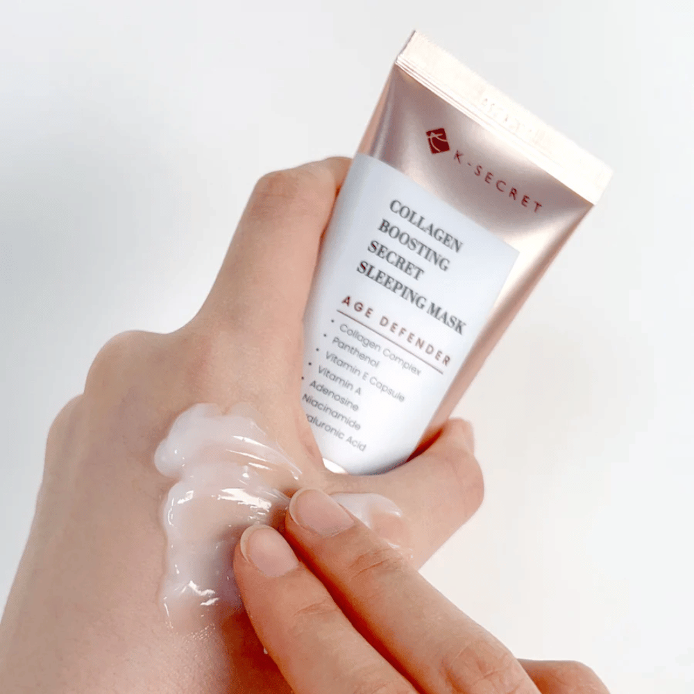 One hand holds Collagen Boosting Secret Sleeping Mask while the other applies a generous amount of cream on the back of the hand – showing the product's consistency and application.