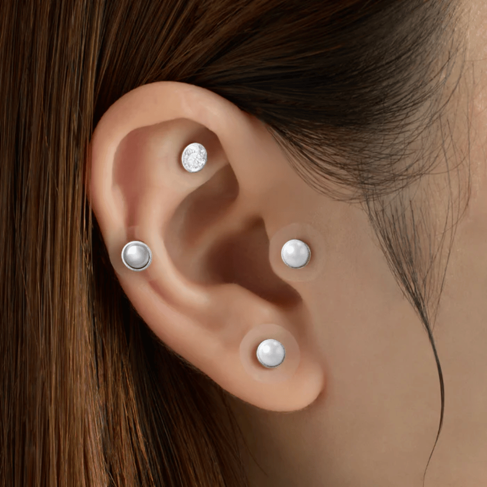 Close-up of an ear with several RETURNITY Ear Therapy Acupressure Patch applied to different areas of the ear for acupressure and a stylish look.
