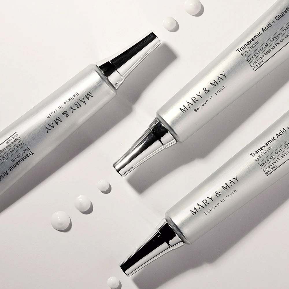 Styled product image of Mary&May Tranexamic Acid + Glutathione Eye Cream showing the cream's texture and focus on brightening eye care.