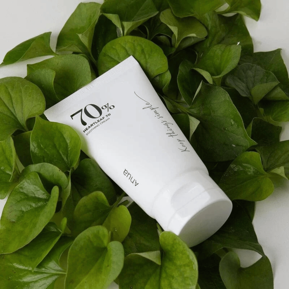 A tube of Heartleaf 70% Soothing Cream rests on a bed of green leaves.
