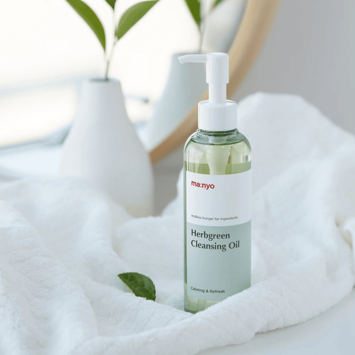 ma:nyo Herbgreen Cleansing Oil in pump bottle placed on white towel, soothing cleansing oil with herb-based ingredients for gentle face wash