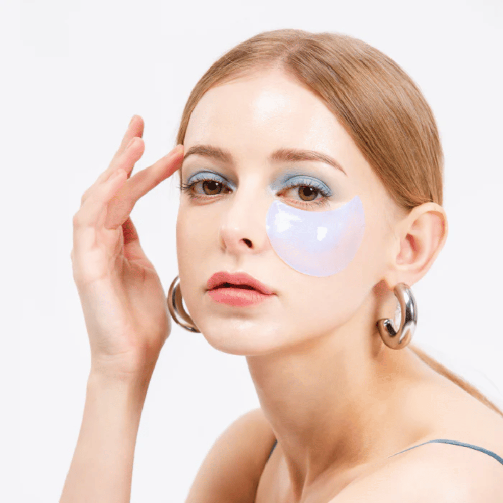Modell bär ett blåskimrande hydrogel eye patch under ögat för uppfriskande effekt.