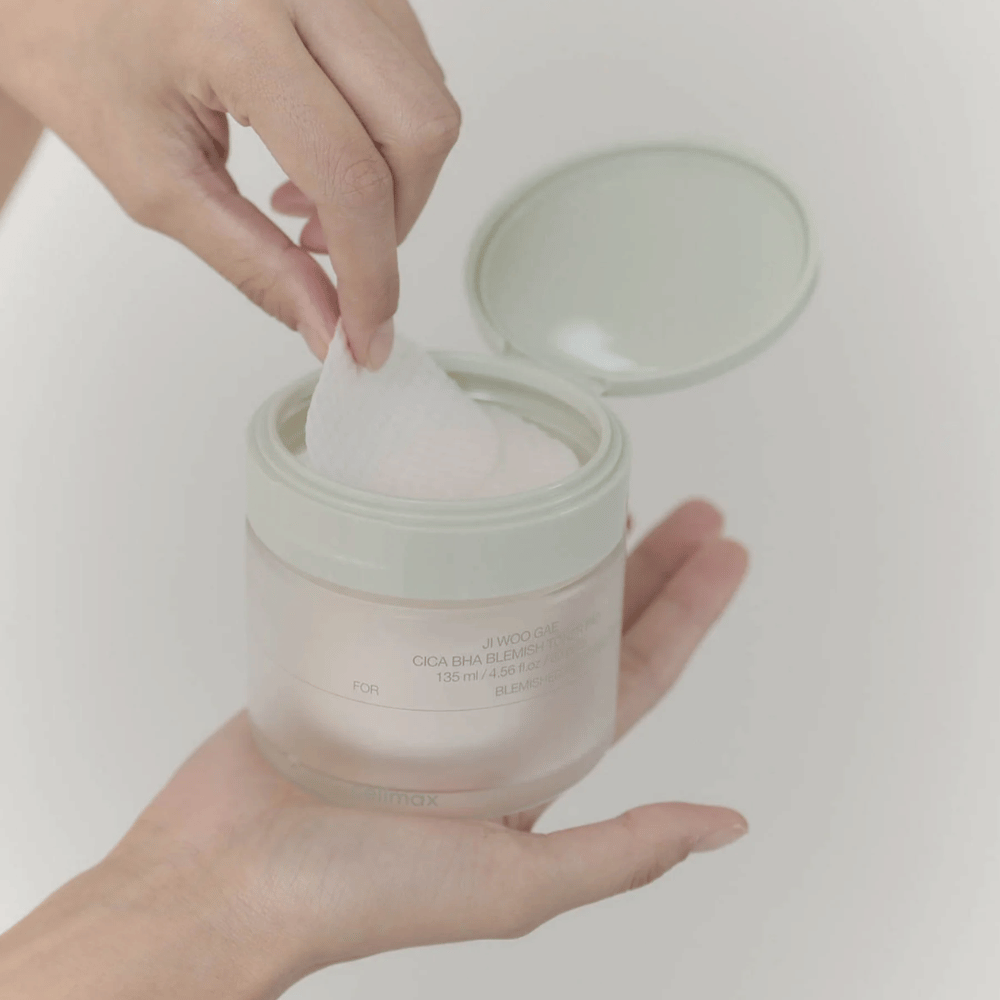 Hand picks up a toner pad from the jar Celimax Ji Woo Gae Cica BHA Blemish Toner Pad, perfect for impure skin.