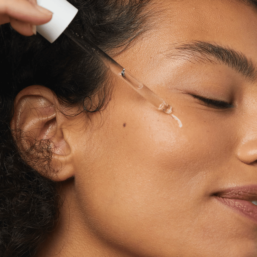 Woman applies Skin1004 Madagascar Centella Hyalu-Cica First Ampoule to her cheek with a dropper.