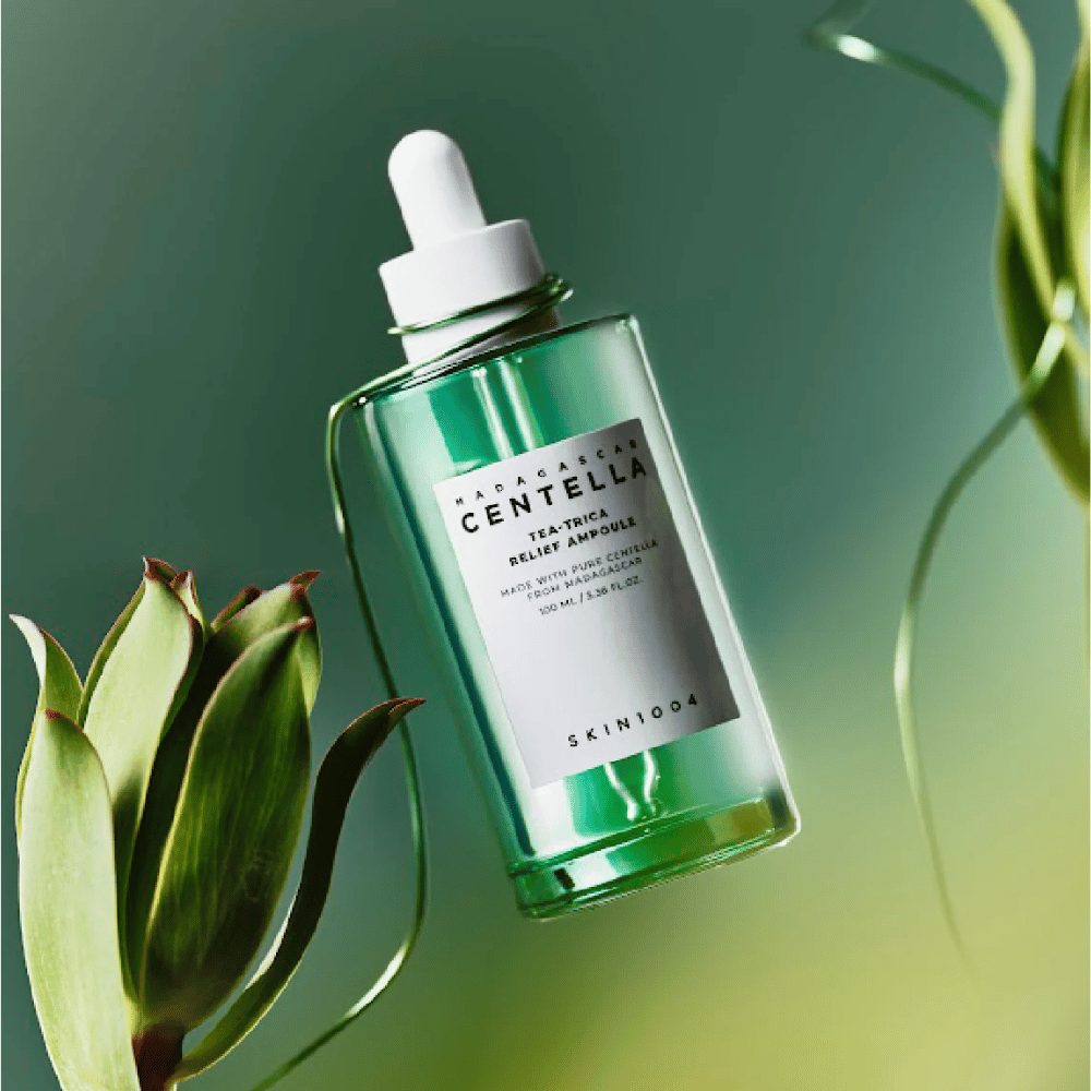 SKIN1004 Madagascar Centella Tea-Trica Relief Ampoule – grön glasflaska med pipett, vit etikett och 100 ml innehåll, fotograferad mot grön bakgrund med växtdetaljer.