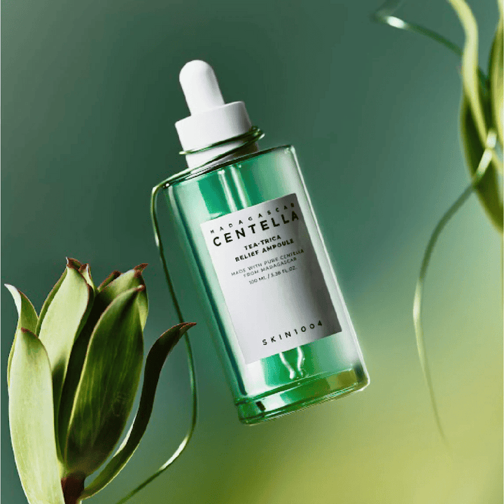 SKIN1004 Madagascar Centella Tea-Trica Relief Ampoule – grön glasflaska med pipett, vit etikett och 100 ml innehåll, fotograferad mot grön bakgrund med växtdetaljer.
