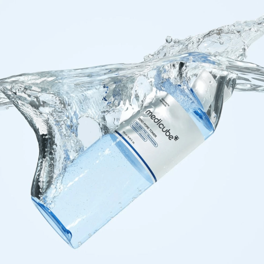Medicube Zero Pore Toner 250 ml, exfoliating toner with AHA, BHA and PHA. Transparent blue bottle surrounded by a large splash of water.