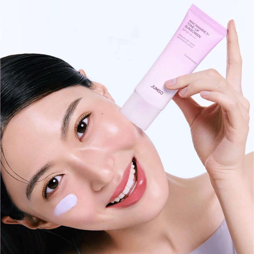 Model applies JUMISO Niacinamide 3+ Tone-Up Sunscreen SPF50+ PA++++ for UV protection, a more even skin tone, and natural radiance.