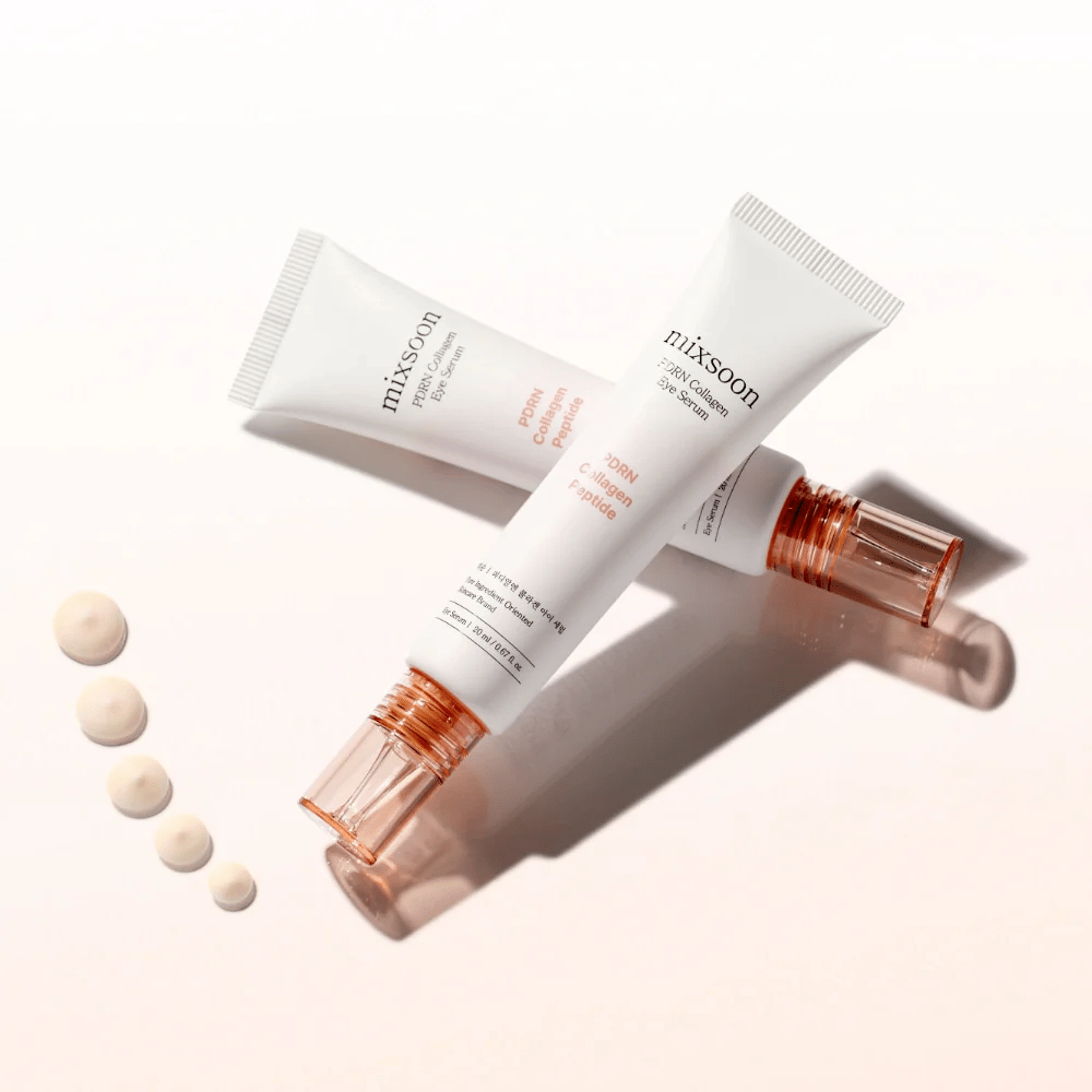 Two tubes of Mixsoon PDRN Collagen Eye Serum lie crossed with small drops of the serum. A light eye treatment that moisturizes and smooths out lines.