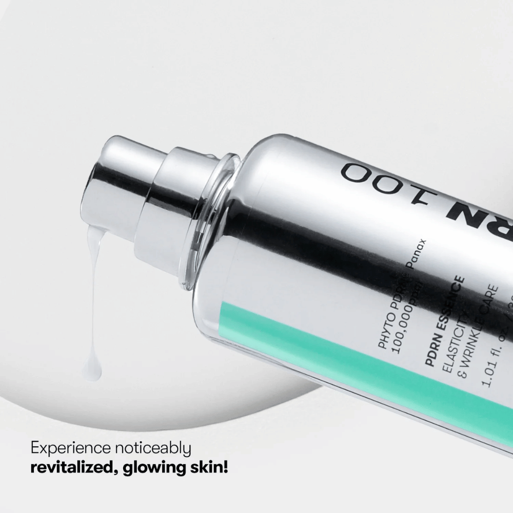 Close-up of a silver-colored pump bottle with VT PDRN Essence 100. A white essence flows out from the nozzle, and the text on the image reads: "Experience noticeably revitalized, glowing skin!"