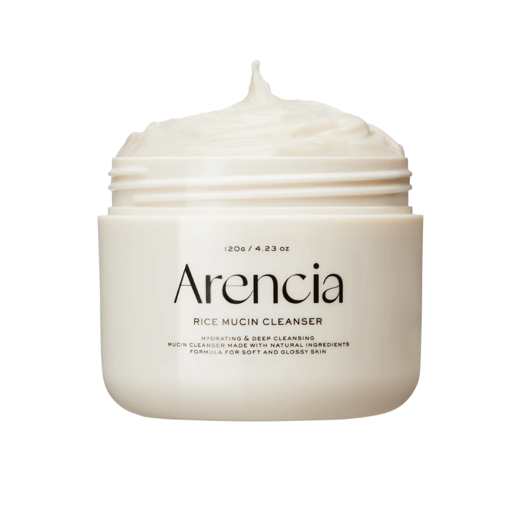Product image of Arencia Rice Mucin Cleanser in a white jar with creamy, whipped texture peeking out from the opening. Text on the packaging emphasizes hydration and deep cleansing.