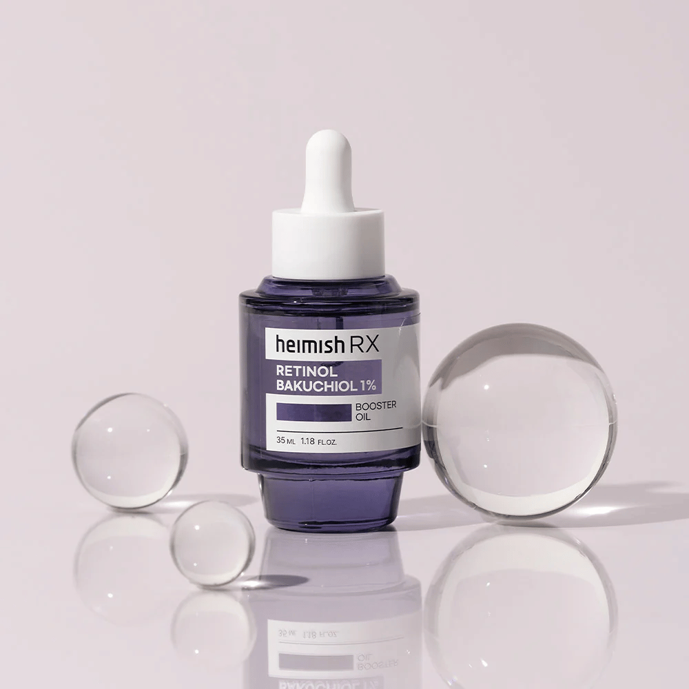 Heimish RX Retinol Bakuchiol Booster Oil 1% in an elegant purple glass bottle with a pipette. The oil is placed on a reflective surface with glass beads around it, giving a luxurious and modern feel.
