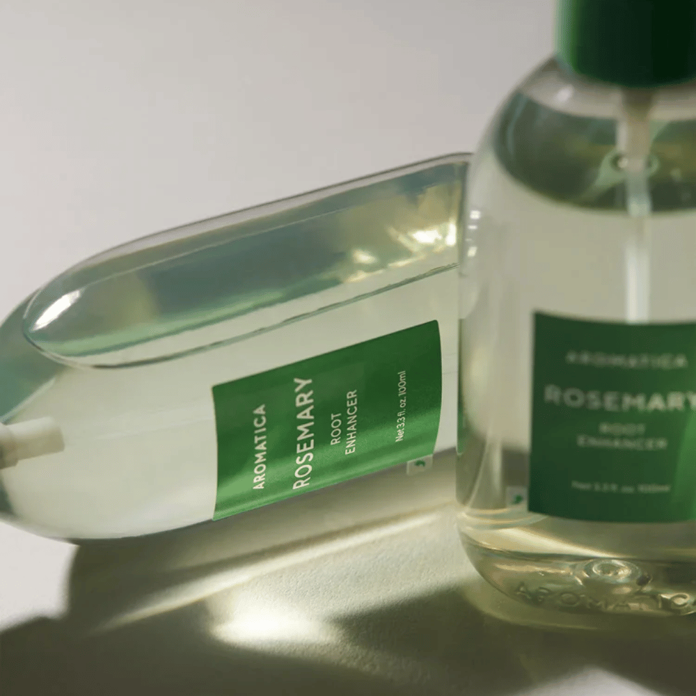 Two AROMATICA Rosemary Root Enhancer bottles with a transparent protective cap and green label. Close-up highlighting the product's premium design and natural hair care concept.