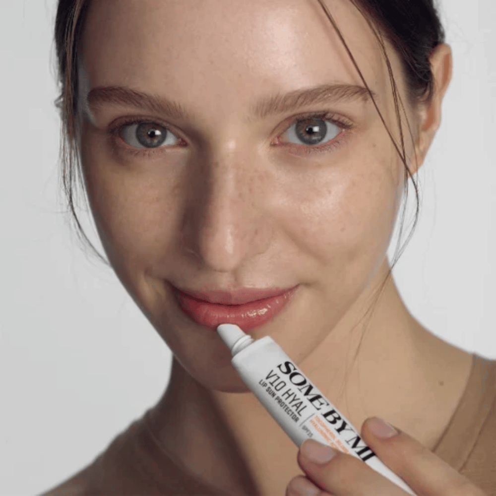 A woman holds a tube V10 Hyal Lip Sun Protector SPF15 7ml lip balm for sun protection and moisturizing, by SOME BY MI.