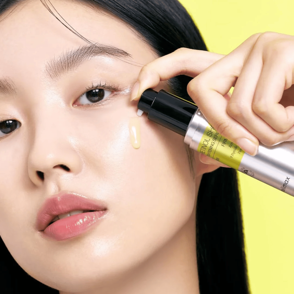 Model applies The Vita-A Retinol Shot Tightening Serum from Tiam near the eye area, focusing on the skin's radiance and the serum's yellow consistency.