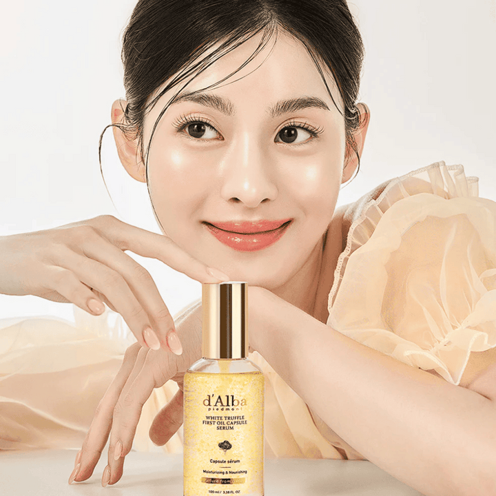 Modell i ljus klänning ler mjukt bredvid d'Alba White Truffle First Oil Capsule Serum.