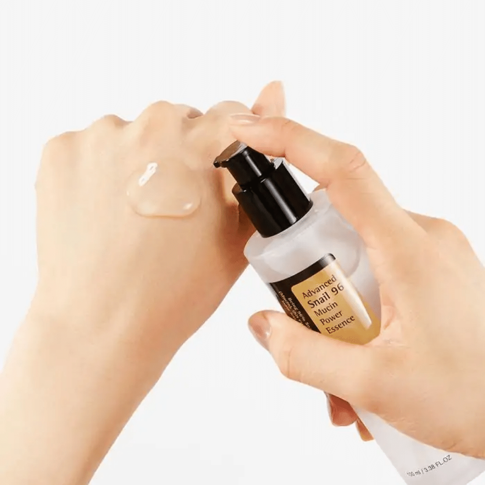 En hand håller i en flaska COSRX Advanced Snail 96 Mucin Power Essence 100ml hudvårdsprodukt.